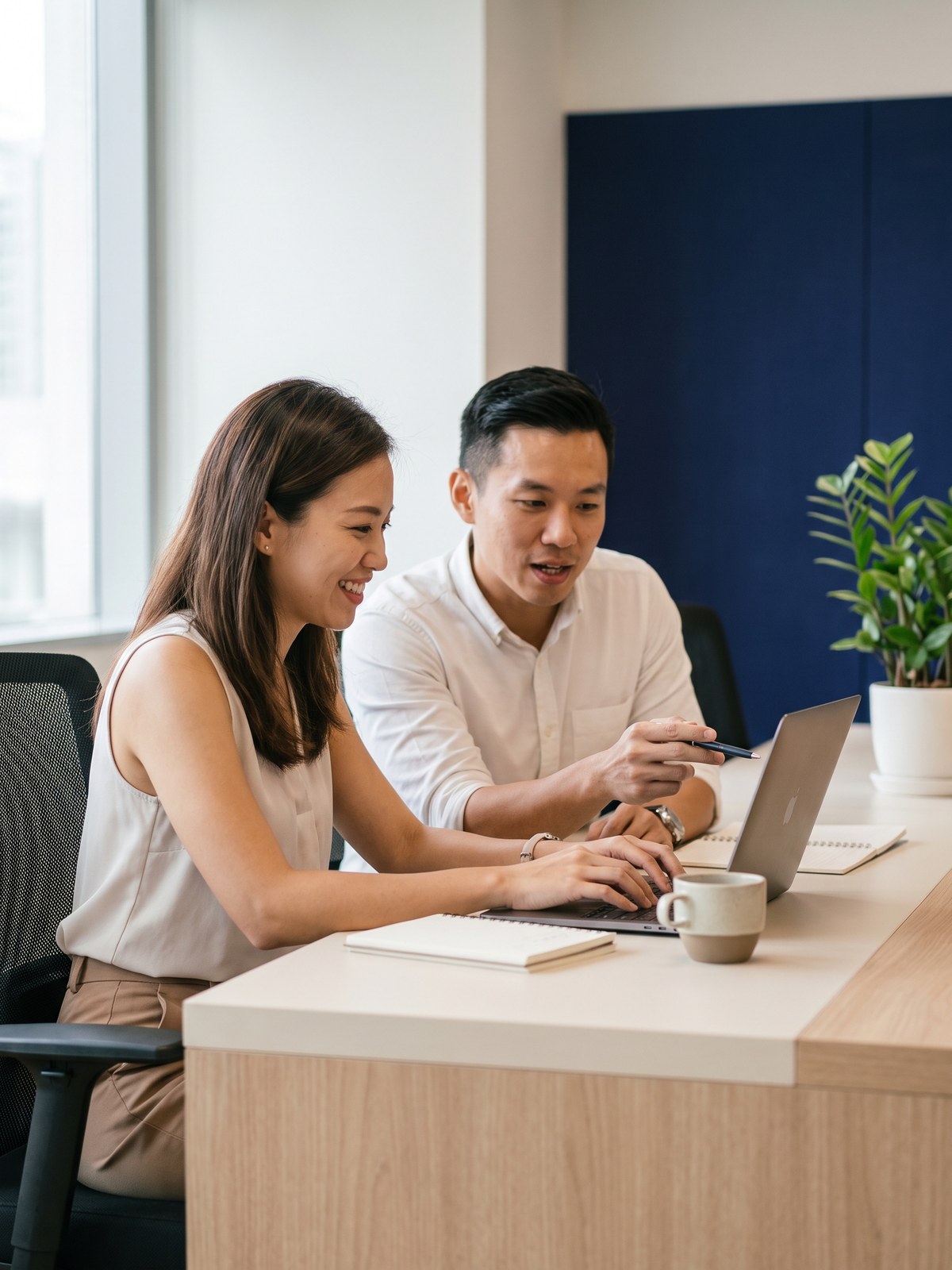 Two professionals learning advanced AI prompting together at a laptop in a Singapore office